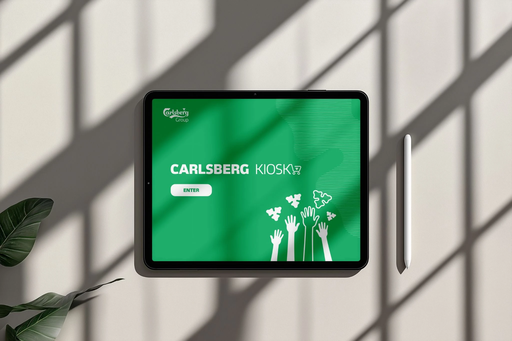 Tablet displaying the Carlsberg Kiosk training welcome screen beside a stylus.